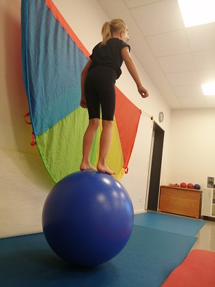 Ein Kind balanciert auf einem großen Ball.